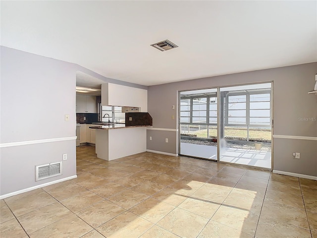 kitchen featuring sink, light tile patterned floors, white cabinets, and kitchen peninsula