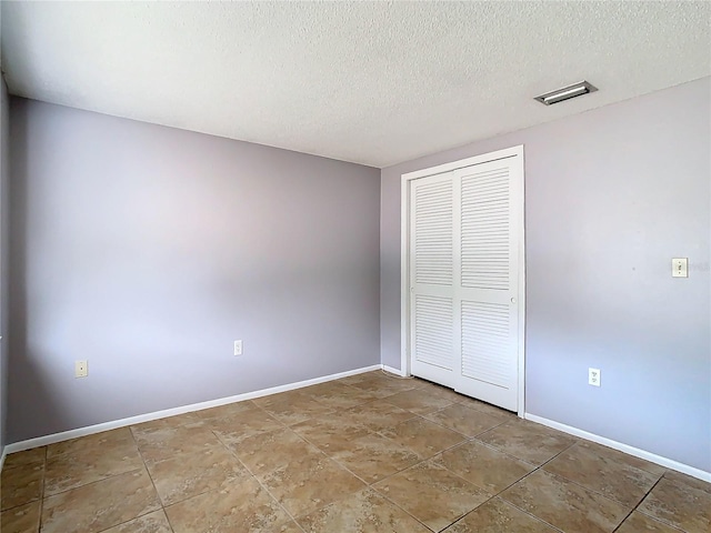 unfurnished bedroom featuring a textured ceiling and a closet