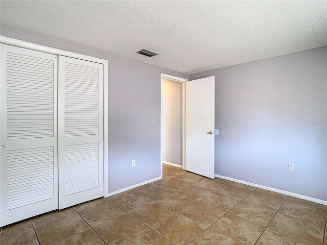 unfurnished bedroom with tile patterned flooring, a closet, and a textured ceiling