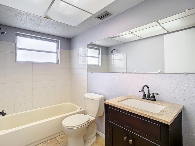 full bathroom with vanity, a textured ceiling, tile patterned floors, toilet, and tiled shower / bath