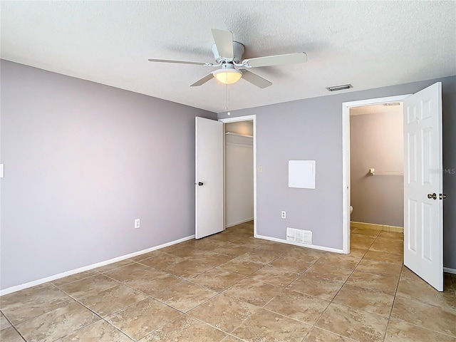 unfurnished bedroom featuring ceiling fan, a closet, a textured ceiling, and light tile patterned flooring