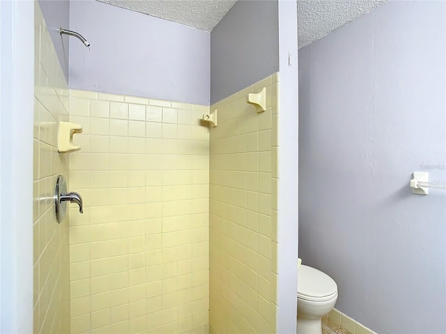 bathroom with a tile shower, a textured ceiling, and toilet