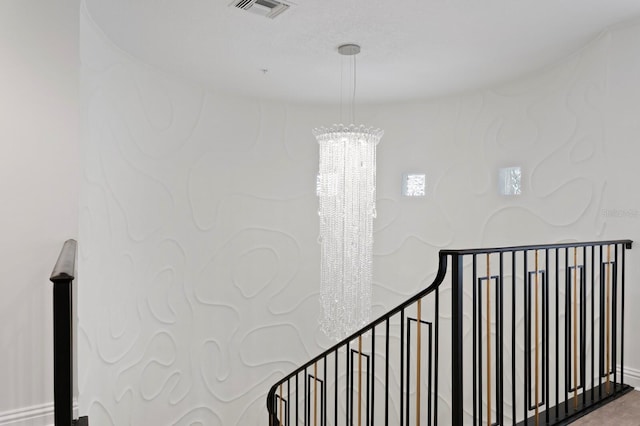 stairway with visible vents, baseboards, and a notable chandelier