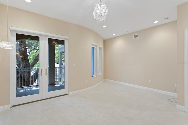 carpeted empty room featuring french doors and a chandelier