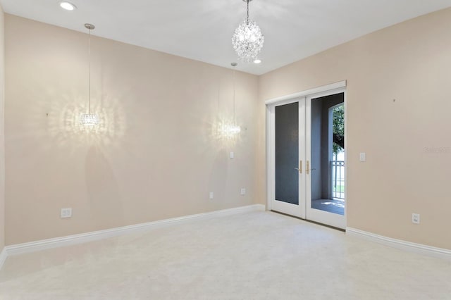 carpeted empty room with french doors and a chandelier