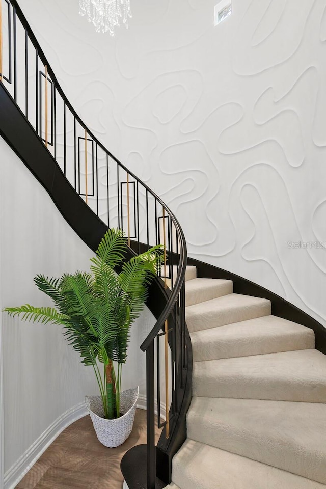 stairway with hardwood / wood-style flooring and a chandelier