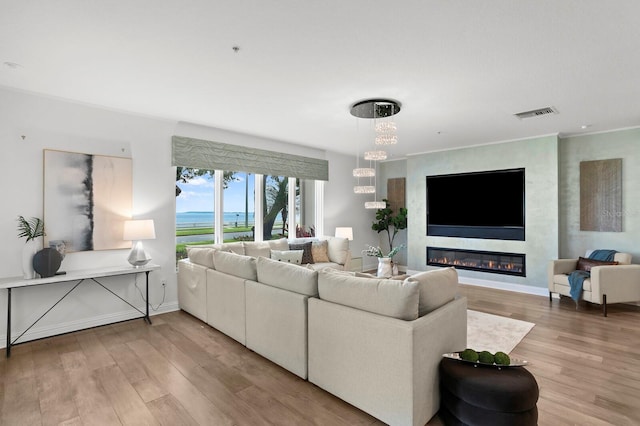 living room with visible vents, light wood-style floors, a fireplace, baseboards, and a chandelier