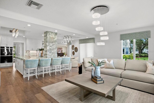 living room with sink, hardwood / wood-style floors, a textured ceiling, and a notable chandelier