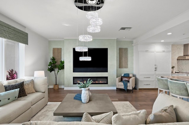 living room with visible vents, wood finished floors, a fireplace, and ornamental molding