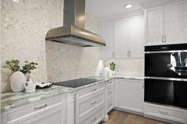 kitchen featuring extractor fan, white cabinetry, tasteful backsplash, light stone countertops, and black appliances