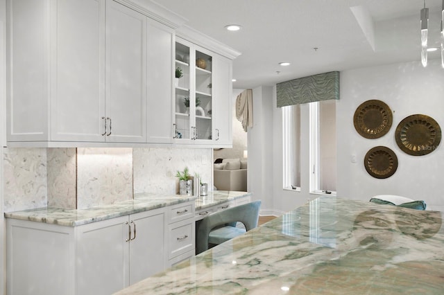 kitchen featuring backsplash, glass insert cabinets, light stone counters, recessed lighting, and white cabinets