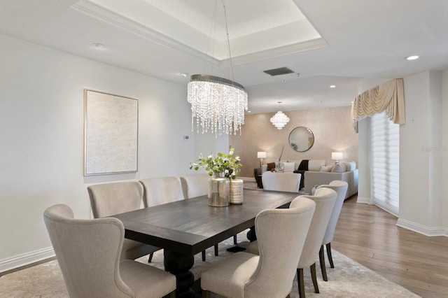 dining area with a tray ceiling, baseboards, visible vents, and light wood-style flooring