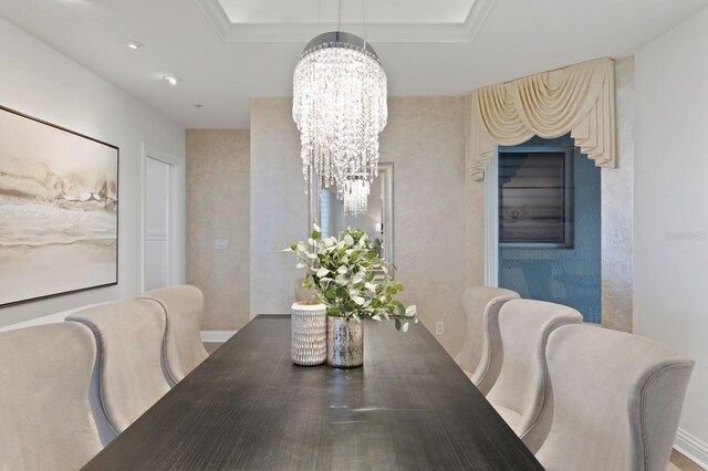 dining space with a raised ceiling, ornamental molding, and a chandelier