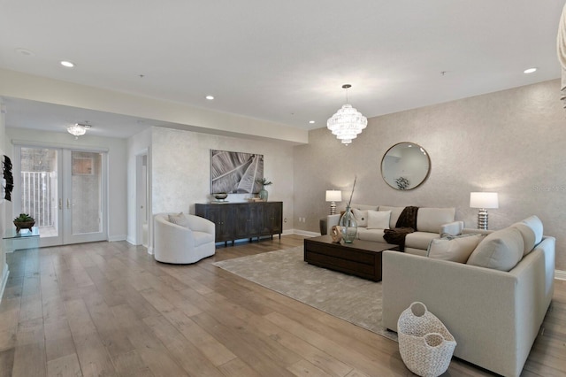 living room with french doors, an inviting chandelier, and light hardwood / wood-style flooring