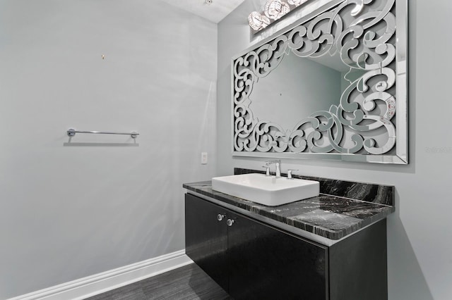 bathroom featuring baseboards, wood finished floors, and vanity