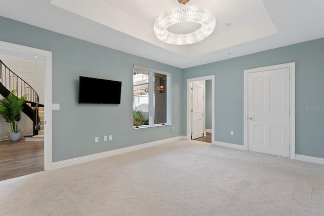 unfurnished bedroom with light colored carpet and a raised ceiling