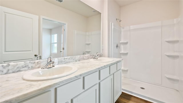 bathroom with hardwood / wood-style floors, walk in shower, and vanity