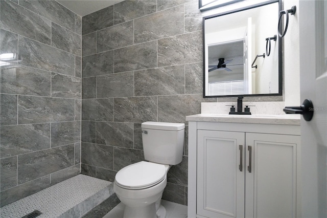 bathroom with tiled shower, toilet, vanity, and tile walls