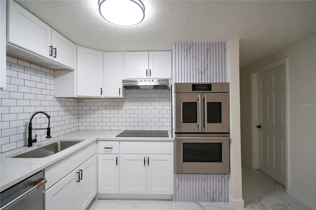 kitchen featuring sink, tasteful backsplash, white cabinetry, a textured ceiling, and stainless steel appliances