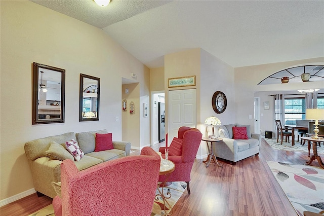 living room with vaulted ceiling, hardwood / wood-style floors, and a textured ceiling