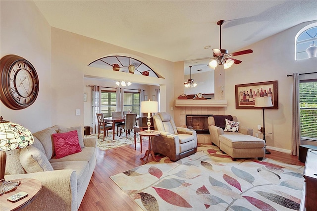 living room with a tile fireplace, plenty of natural light, high vaulted ceiling, and light hardwood / wood-style floors