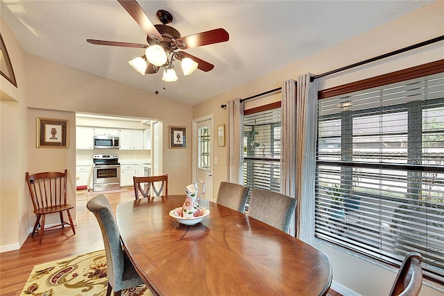 dining space featuring lofted ceiling, ceiling fan, light hardwood / wood-style floors, and a textured ceiling