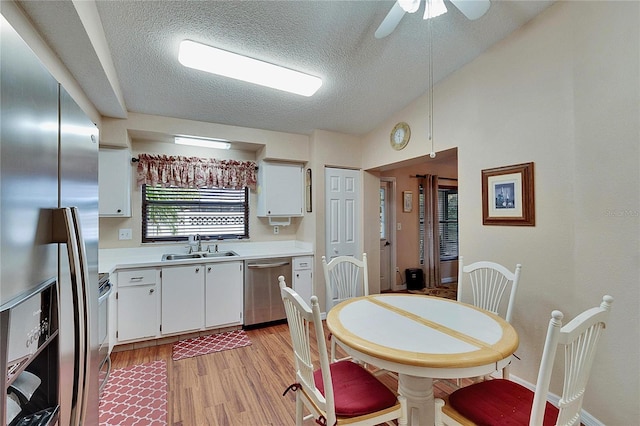 kitchen featuring vaulted ceiling, white cabinetry, sink, stainless steel appliances, and light wood-type flooring