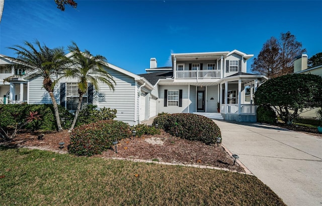 view of front of property featuring a garage, a balcony, covered porch, and a front lawn