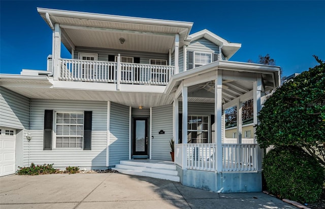 view of front facade with a porch, a garage, and a balcony