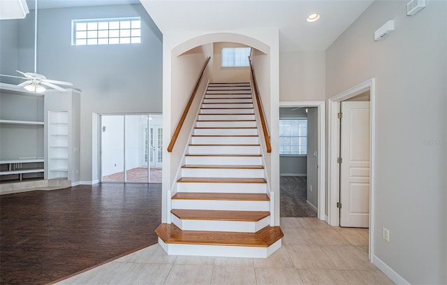 staircase featuring a towering ceiling, ceiling fan, and hardwood / wood-style flooring