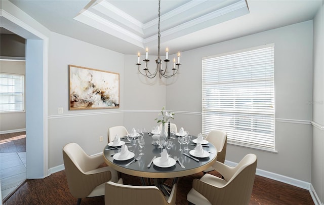 dining area featuring crown molding, dark hardwood / wood-style floors, a raised ceiling, and a chandelier