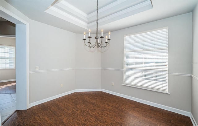 empty room featuring crown molding, dark hardwood / wood-style floors, a chandelier, and a tray ceiling