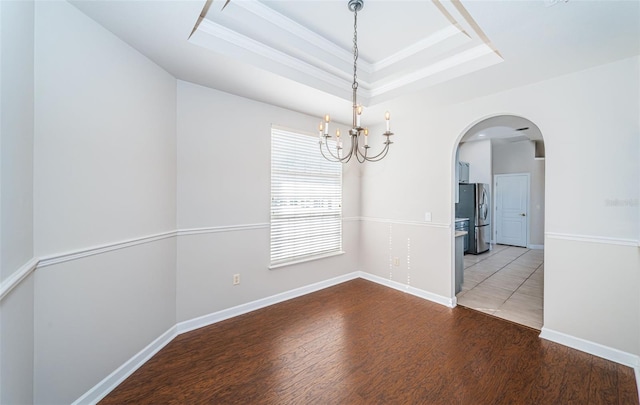 empty room featuring ornamental molding, a tray ceiling, dark hardwood / wood-style flooring, and a notable chandelier