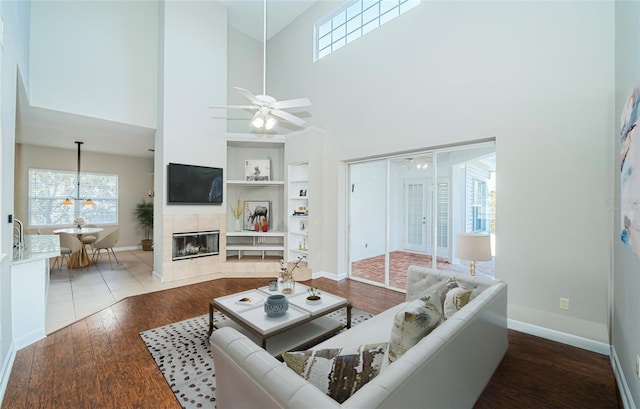 living room with hardwood / wood-style flooring, ceiling fan, a fireplace, and built in shelves