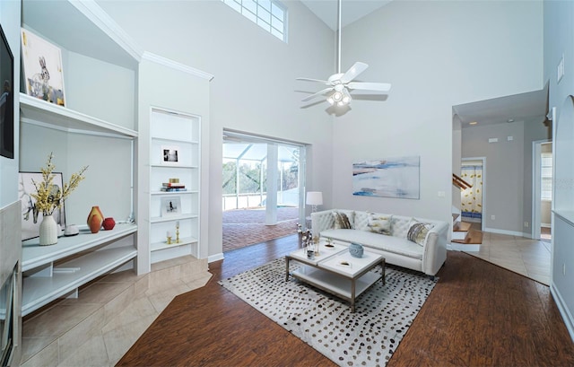 living room featuring hardwood / wood-style flooring, a towering ceiling, built in features, and ceiling fan