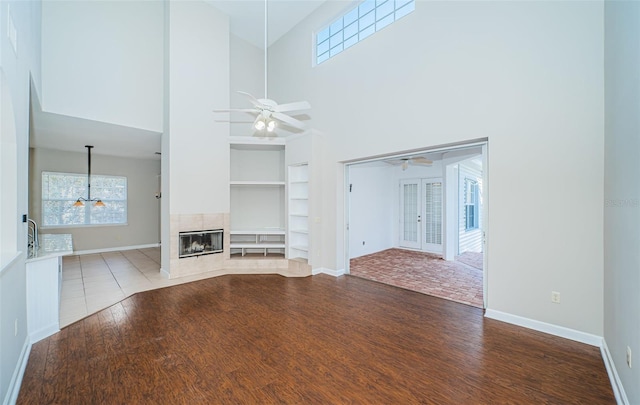 unfurnished living room with hardwood / wood-style flooring, ceiling fan, a healthy amount of sunlight, and a tile fireplace