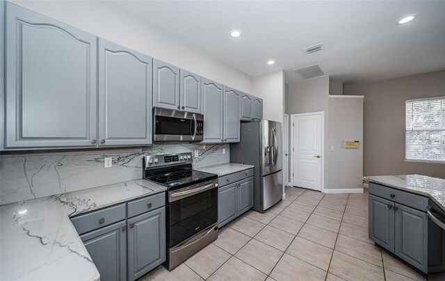 kitchen featuring light stone counters, appliances with stainless steel finishes, tasteful backsplash, and gray cabinetry