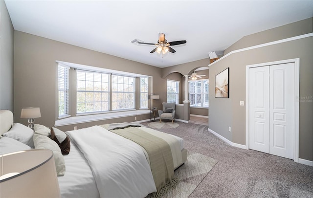 bedroom with ceiling fan, light colored carpet, lofted ceiling, and a closet