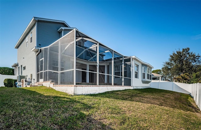 rear view of property featuring central AC, a lawn, and glass enclosure