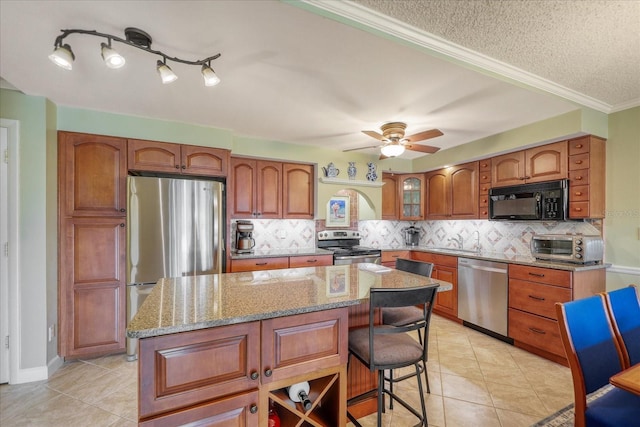 kitchen featuring a center island, light tile patterned floors, backsplash, stainless steel appliances, and light stone counters