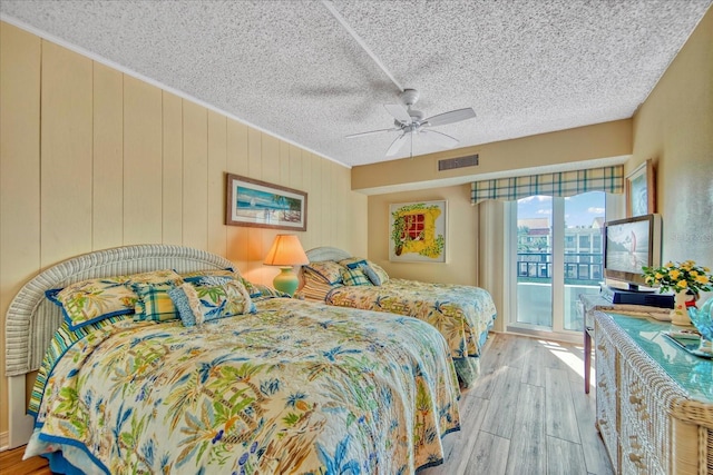 bedroom featuring ceiling fan, access to exterior, a textured ceiling, and light wood-type flooring