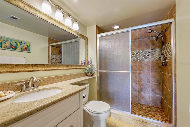 bathroom featuring toilet, a shower with shower door, tile patterned floors, and vanity