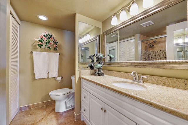 bathroom with toilet, vanity, tiled shower, and tile patterned flooring