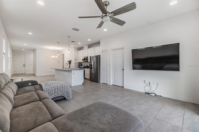 living room with ceiling fan with notable chandelier and light tile patterned floors