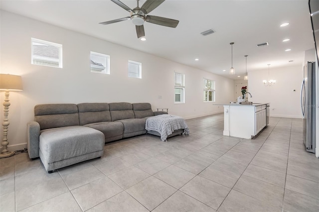 tiled living room with sink and ceiling fan with notable chandelier