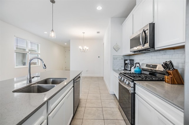 kitchen featuring pendant lighting, appliances with stainless steel finishes, sink, white cabinets, and light tile patterned floors