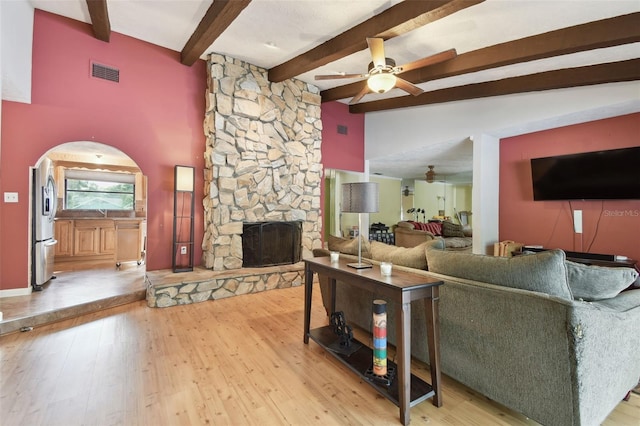 living room with ceiling fan, light hardwood / wood-style flooring, lofted ceiling with beams, and a fireplace