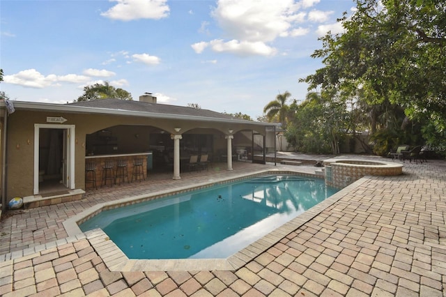 view of pool with an in ground hot tub, a patio, and an outdoor bar