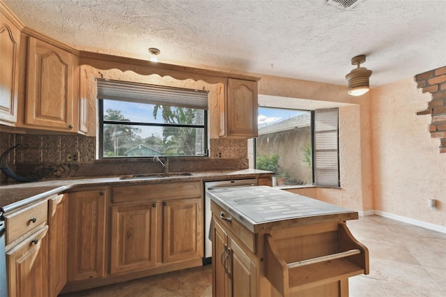 kitchen with sink, dishwasher, decorative backsplash, and a textured ceiling