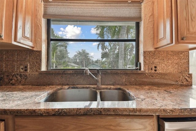 kitchen featuring sink, dark stone countertops, and dishwasher